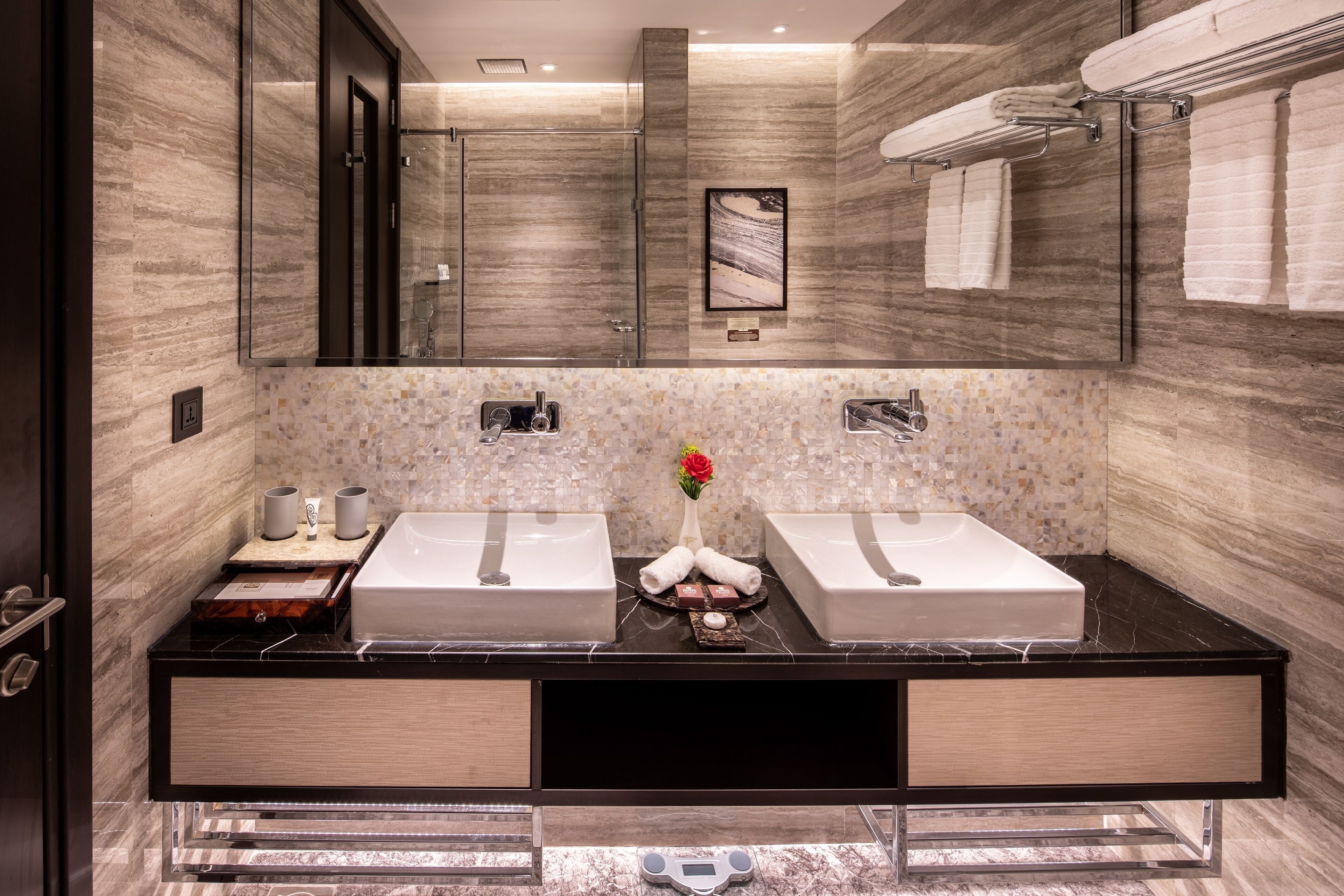 A modern bathroom with two sinks, a large mirror, and a decorative vase.