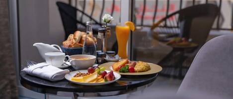 A breakfast table with croissants, fruit, and a glass of orange juice.