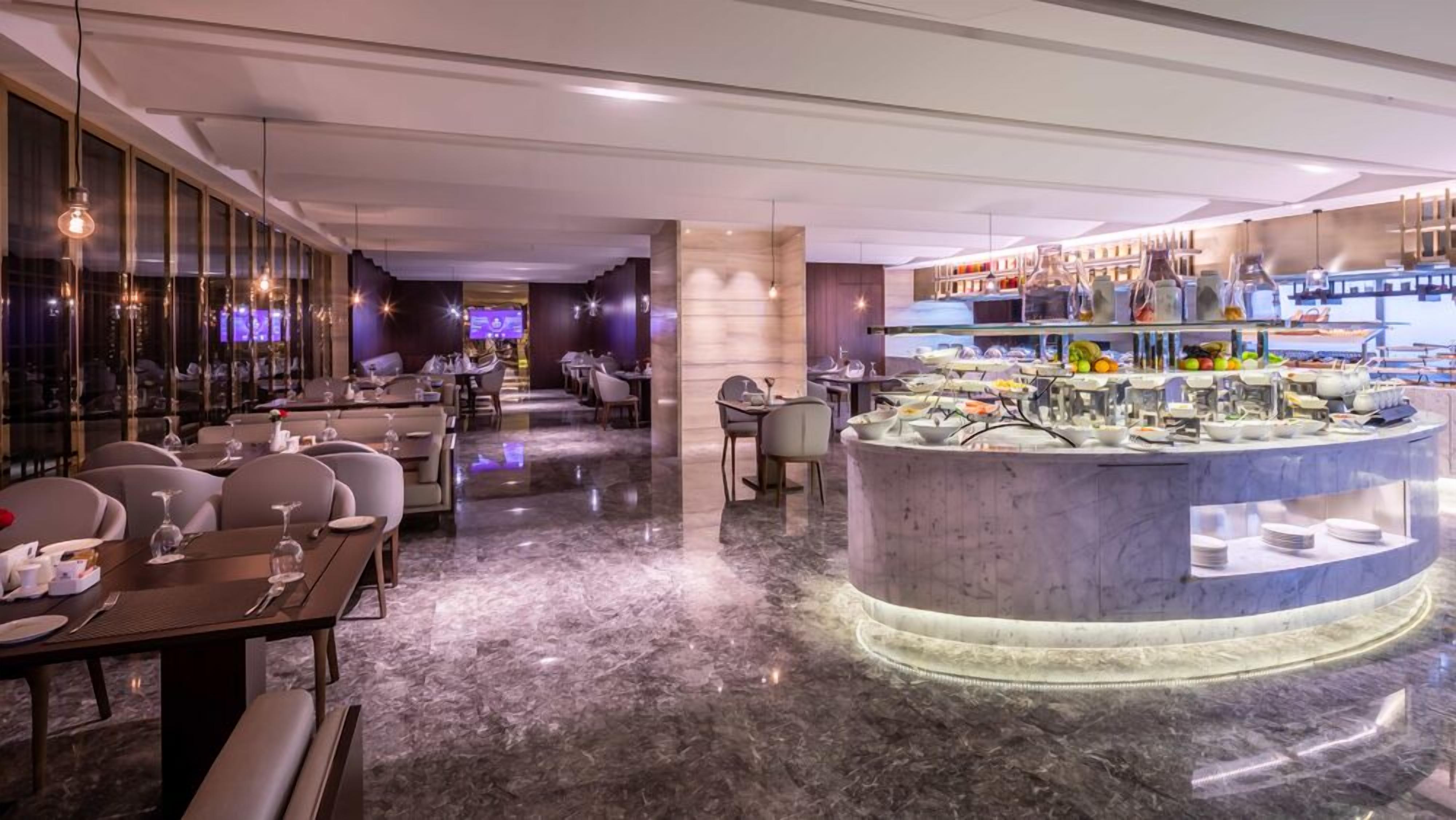 A modern restaurant with a marble floor, dining tables, and a buffet area.