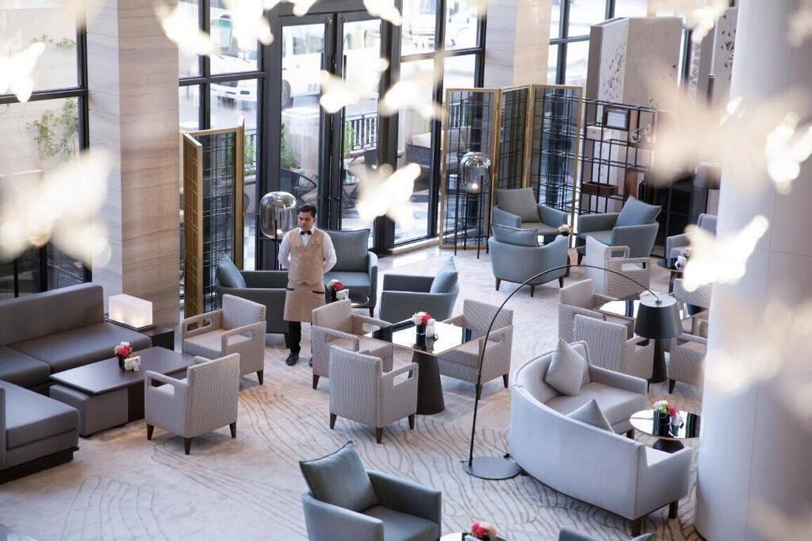 A modern hotel lobby with a variety of seating options, including sofas and armchairs, arranged around a central coffee table.