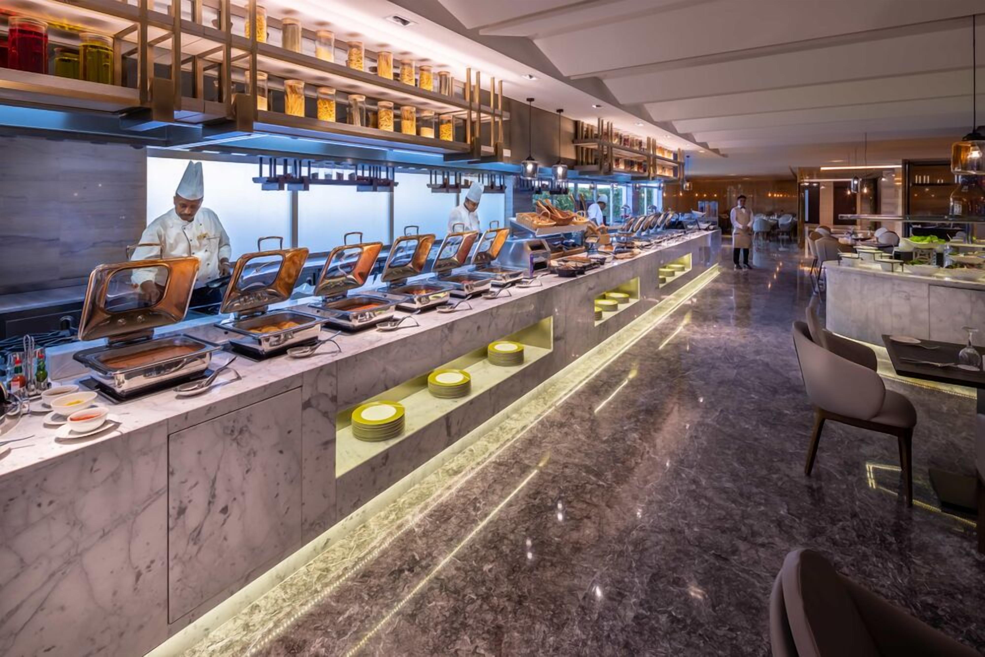 A buffet setup with multiple serving stations, a marble floor, and a modern interior design.