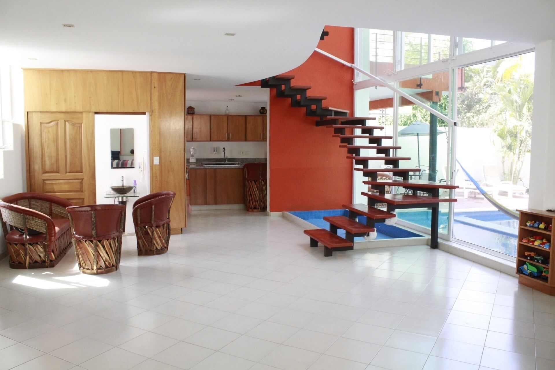 Ein modernes Interieur mit einer Holzes Essecke, einer Küche und einer einzigartigen Treppe, die auf einen Balkon führt.