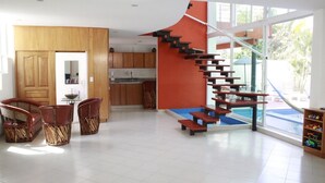 Een modern interieur met een houten eethoek, een keuken en een bijzondere trap die naar een balkon leidt.
