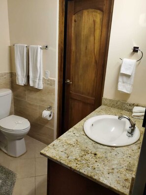 Un baño con inodoro, lavamanos y puerta de madera.