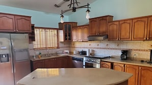 Una cocina con armarios de madera, un refrigerador de acero inoxidable, una estufa y un lavamanos.
