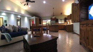 Un espacio habitable amplio con sofá, mesa de centro, mesa de comedor y zona de cocina.