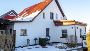 Une maison blanche avec un toit rouge, une antenne parabolique et un fourgon garé.