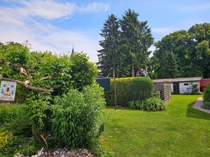A well-maintained garden with a variety of plants, a neatly trimmed hedge, and a small building with a tiled roof. - dog-friendly vacation home - vacation home (Kröslin)