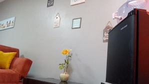 A living room with a sofa, a coffee table, a television, and a wall with decorative items.
