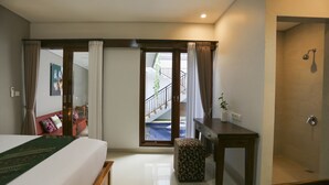 Ein Hotelzimmer mit einem Bett, einer Holzbank, einem kleinen Tisch und einer Tür, die auf einen Balkon führt.