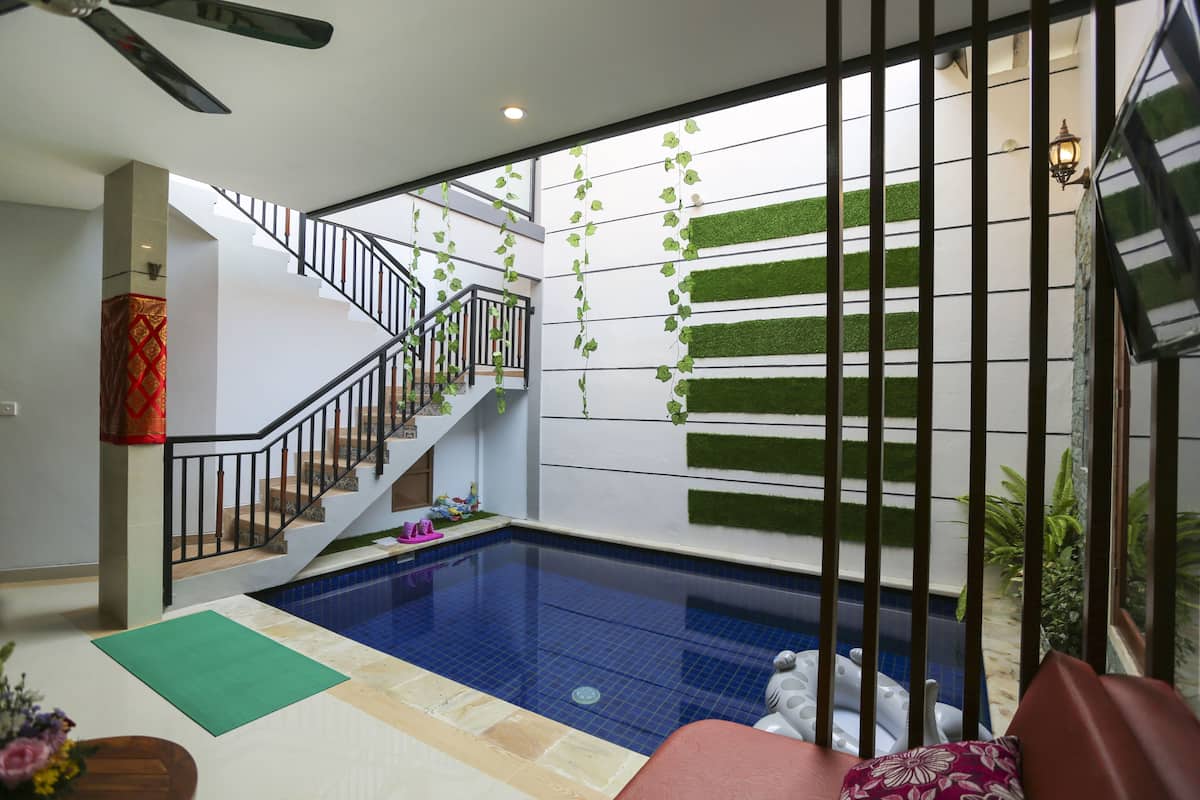 A swimming pool area with a staircase, green wall decorations, and a ceiling fan.