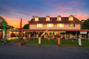 A two-story building with a flat roof and multiple windows, featuring storefronts for businesses like a record shop and a vintage store. - Land of Lost Treasure - Holiday House (Balmoral Ridge)