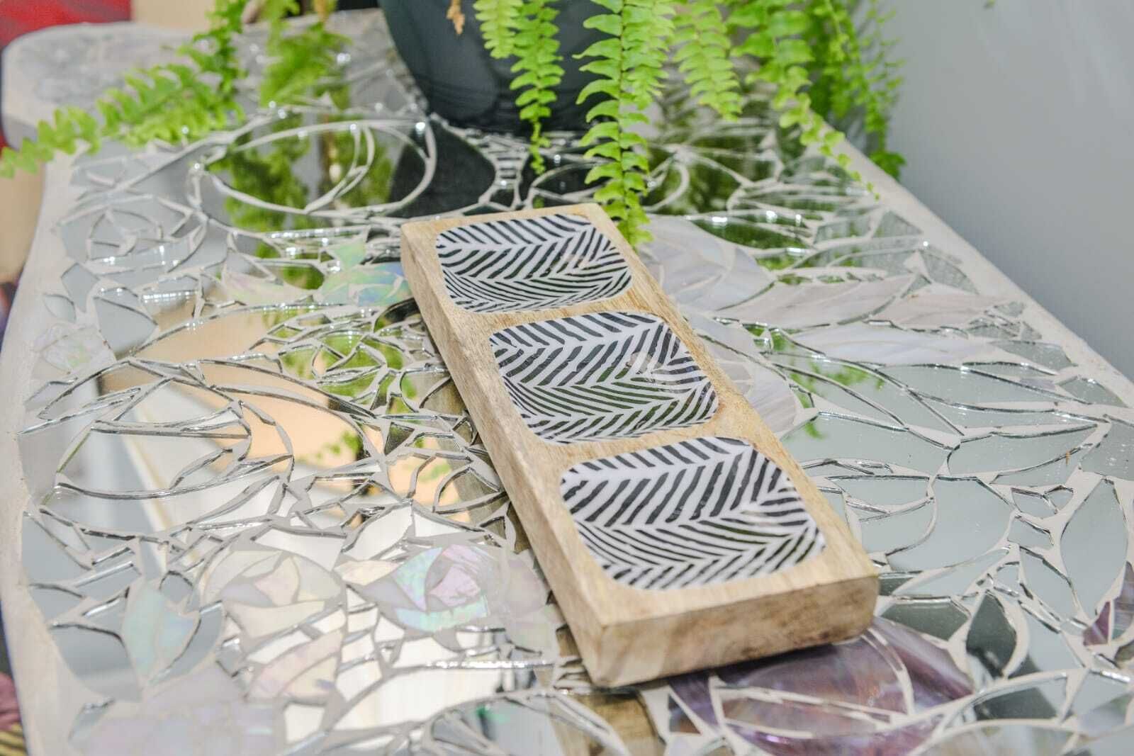 Una mesa con tablero de mosaico y un bloque de madera con diseño de hoja.