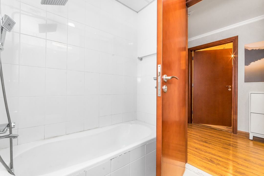 Un baño con bañera, ducha y puerta de madera.