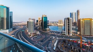 A cityscape with modern high-rise buildings, a river, and a highway.