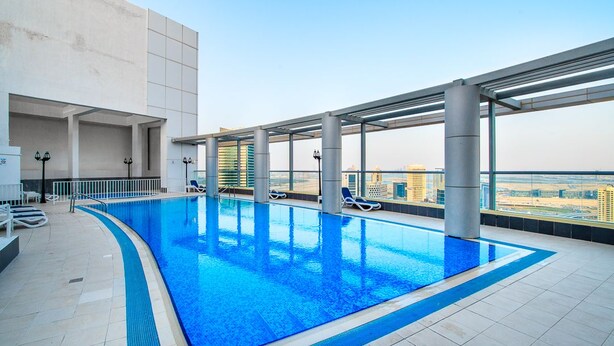 An indoor swimming pool with clear blue water, surrounded by a modern architectural design with large windows offering views of the cityscape.