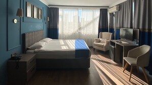 A modern hotel room with a large bed, a desk, a chair, and a TV. - Bloom Hotel (Ankara)