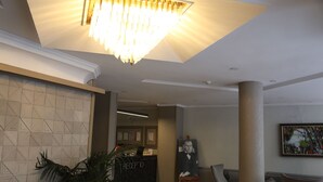 A lobby with a reception desk, a chandelier, a painting, and seating areas. - Bloom Hotel (Ankara)