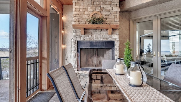 Un patio amplio con chimenea de piedra, techo de madera y ventilador de techo.