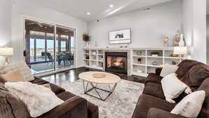 Una sala de estar moderna con chimenea, un ventanal grande y vistas al exterior.