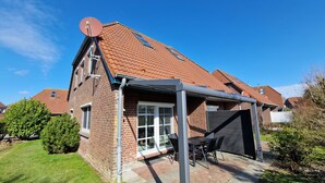 Ein zweistöckiges Haus mit Ziegelaußenwand, einem Ziegeldach und einer überdachten Veranda mit Tisch und Stühlen.
