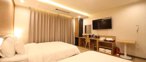 A hotel room with two beds, a desk, a chair, a television, and a fire extinguisher.