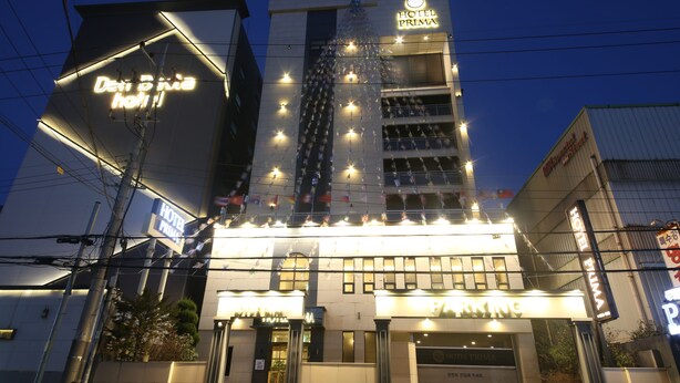 A hotel with a prominent sign for "HOTEL PRIMA" and a parking area. - Hotel Prima (Busan)