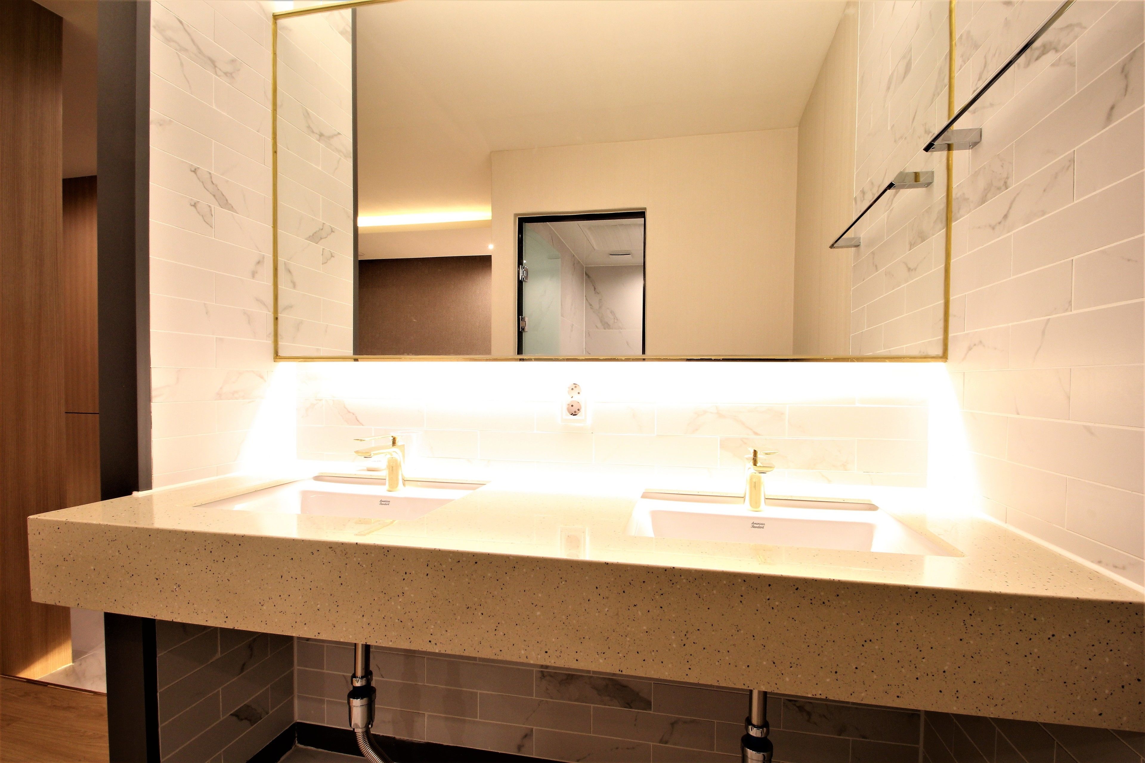 Un bagno moderno con due lavandini, uno specchio grande e una porta che dà su un'altra stanza.