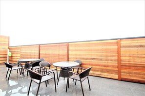 An outdoor patio with a round table and six wicker chairs.