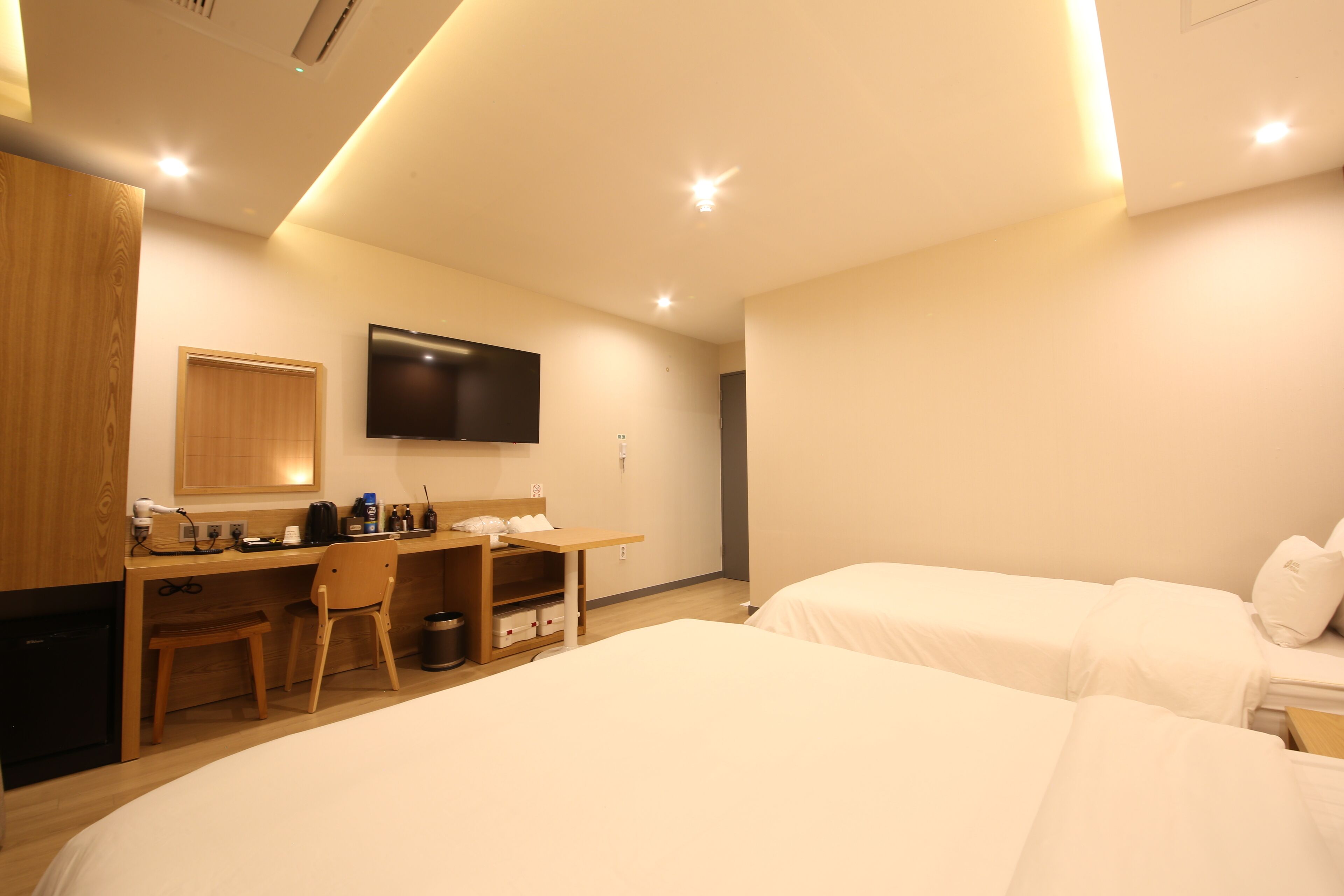 A hotel room with a desk, chair, and two beds.