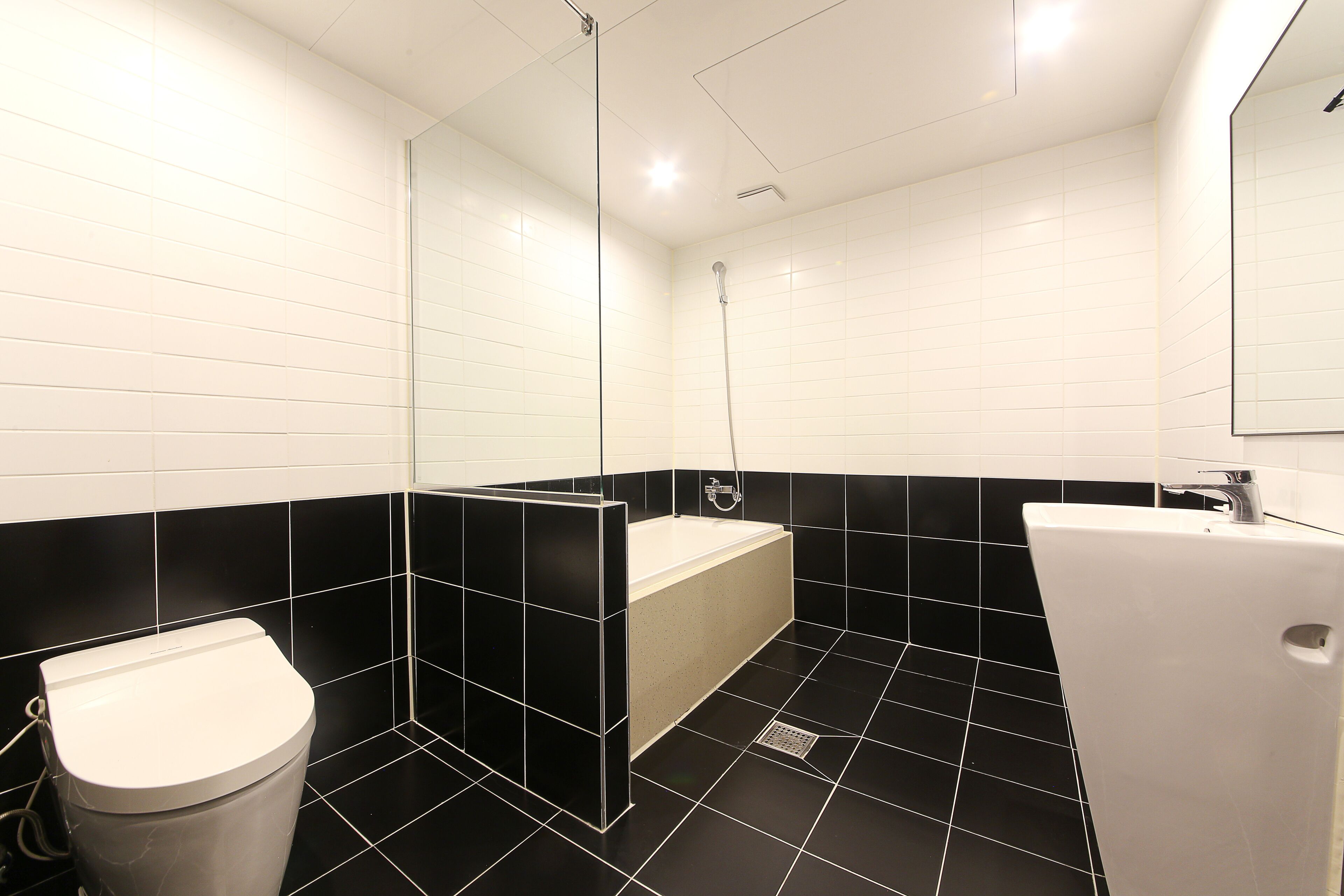 A modern bathroom with a toilet, bathtub, and sink.