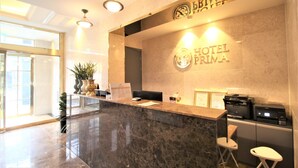 A hotel reception desk with a marble counter, a reception area, and a sign that reads "HOTEL PRIMA". - Hotel Prima (Busan)