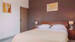 Une chambre d’hôtel avec un lit, deux tables de chevet et deux lampes fixées au mur.