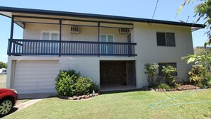 A two-story building with a garage, a balcony, and a small garden area with plants and rocks.