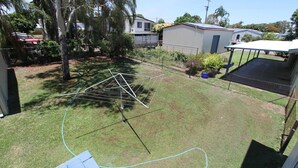 A backyard with a clothesline, a trampoline, and a fenced area with trees and a shed.