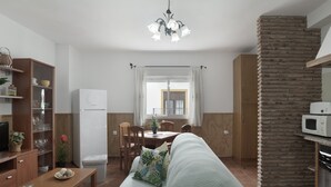 Cozinha moderna com micro-ondas, área de refeições com mesa e cadeiras, sofá e parede de tijolos embutida.