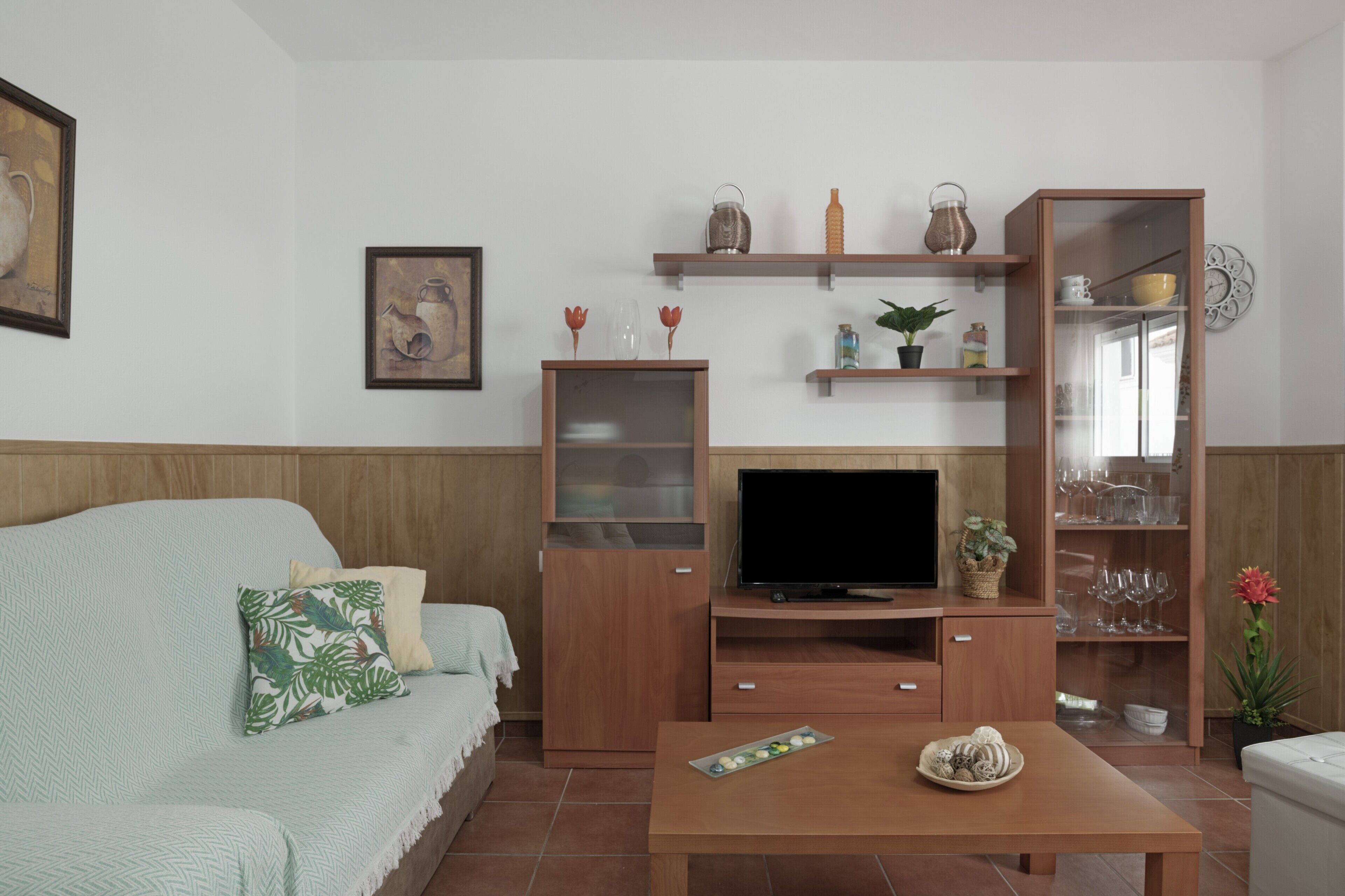 Een woonkamer met een bank, tv-meubel, houten planken en een salontafel.