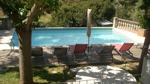 A pool area with lounge chairs and a table, surrounded by trees and a fence. - Separate air-conditioned bedroom, summer kitchen with steps and swimming pool (Sartène)