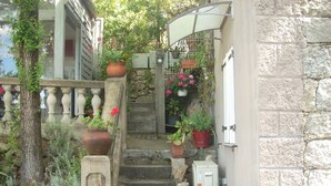 A stone staircase with potted plants, a metal railing, and a stone wall. - Separate air-conditioned bedroom, summer kitchen with steps and swimming pool (Sartène)