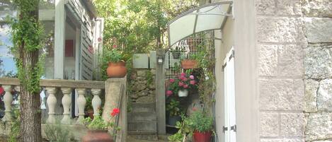 A stone staircase with potted plants, a metal railing, and a stone wall.