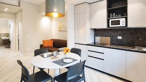 A modern kitchen with white cabinets, a microwave, and a dining area with a round table and chairs. - GuestHost - Delightful one bedroom apartment particularly welcoming, with attention to detail and very bright. It has all the necessary comforts.Located in front of the Maggiore hospital, you can easily reach the historic center, the station, the airport (Bologna)