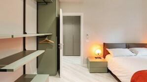 A modern bedroom with a bed, bedside table, and a wardrobe. - GuestHost - Delightful one bedroom apartment particularly welcoming, with attention to detail and very bright. It has all the necessary comforts.Located in front of the Maggiore hospital, you can easily reach the historic center, the station, the airport (Bologna)