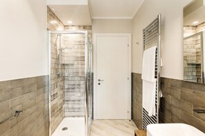 Ein Badezimmer mit Dusche, Toilette, Waschbecken und Handtuchhalter.