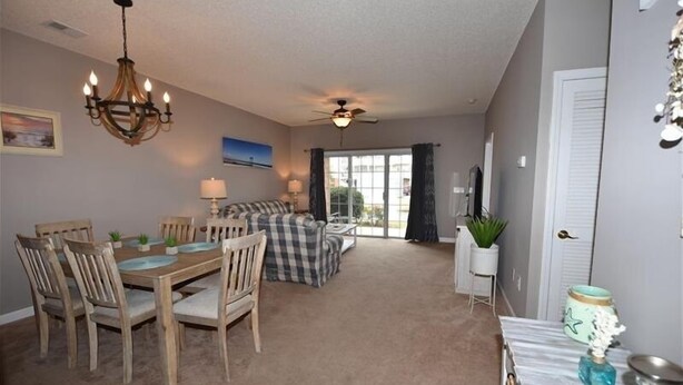 Spiseområde med et træbord og stole, en lysekrone og en ventilator.