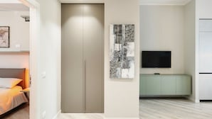 Een moderne kamer met een kledingkast, een flatscreen televisie en een lichtgekleurde vloer.