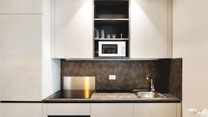 Een moderne keuken met een ingebouwde magnetron, een roestvrijstalen spoelbak en een zwart aanrecht.