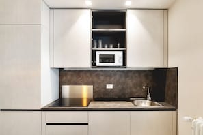A modern kitchen with a built-in microwave, a stainless steel sink, and a black countertop.