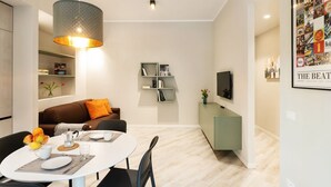 A modern living room with a dining area, a sofa, a TV, and a bookshelf. - GuestHost - New, bright and comfortable apartment near the Ospedale Maggiore and just a few minutes drive from the historic center of Bologna.The neighborhood is full of restaurants, bars and supermarkets and pharmacy.Easily accessible from the motorway  (Bologna)