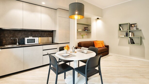 A modern kitchen with a dining area, a microwave, and a round table with chairs. - GuestHost - New, bright and comfortable apartment near the Ospedale Maggiore and just a few minutes drive from the historic center of Bologna.The neighborhood is full of restaurants, bars and supermarkets and pharmacy.Easily accessible from the motorway  (Bologna)
