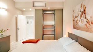 A bedroom with a bed, a nightstand, a dresser, a closet, and a painting on the wall. - GuestHost - New, bright and comfortable apartment near the Ospedale Maggiore and just a few minutes drive from the historic center of Bologna.The neighborhood is full of restaurants, bars and supermarkets and pharmacy.Easily accessible from the motorway  (Bologna)